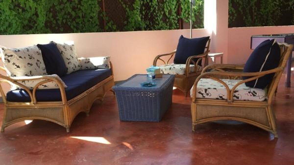 Lounge corner with wicker sofa and armchairs next to a green wall
