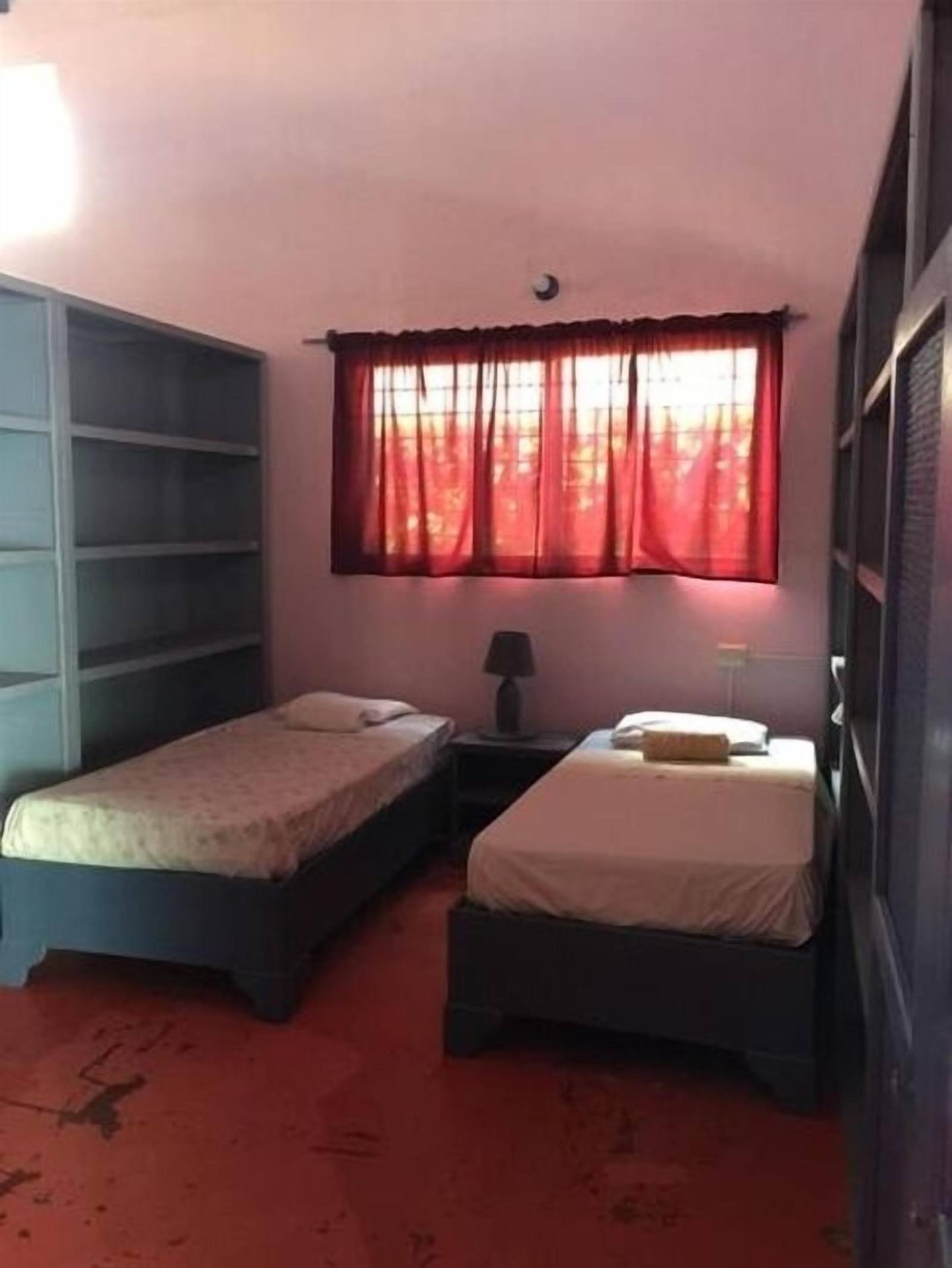 Room with two single beds and a red-curtained window